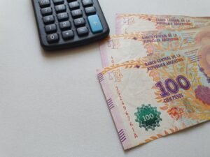 billetes argentinos y monedas con calculadora financiera