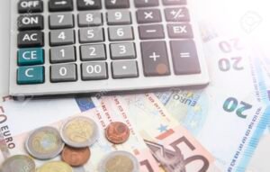 calculadora con billetes y monedas sobre escritorio