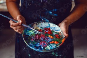 manos sucias sosteniendo pincel y paleta