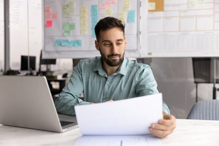 persona revisando documentos con computadora abierta